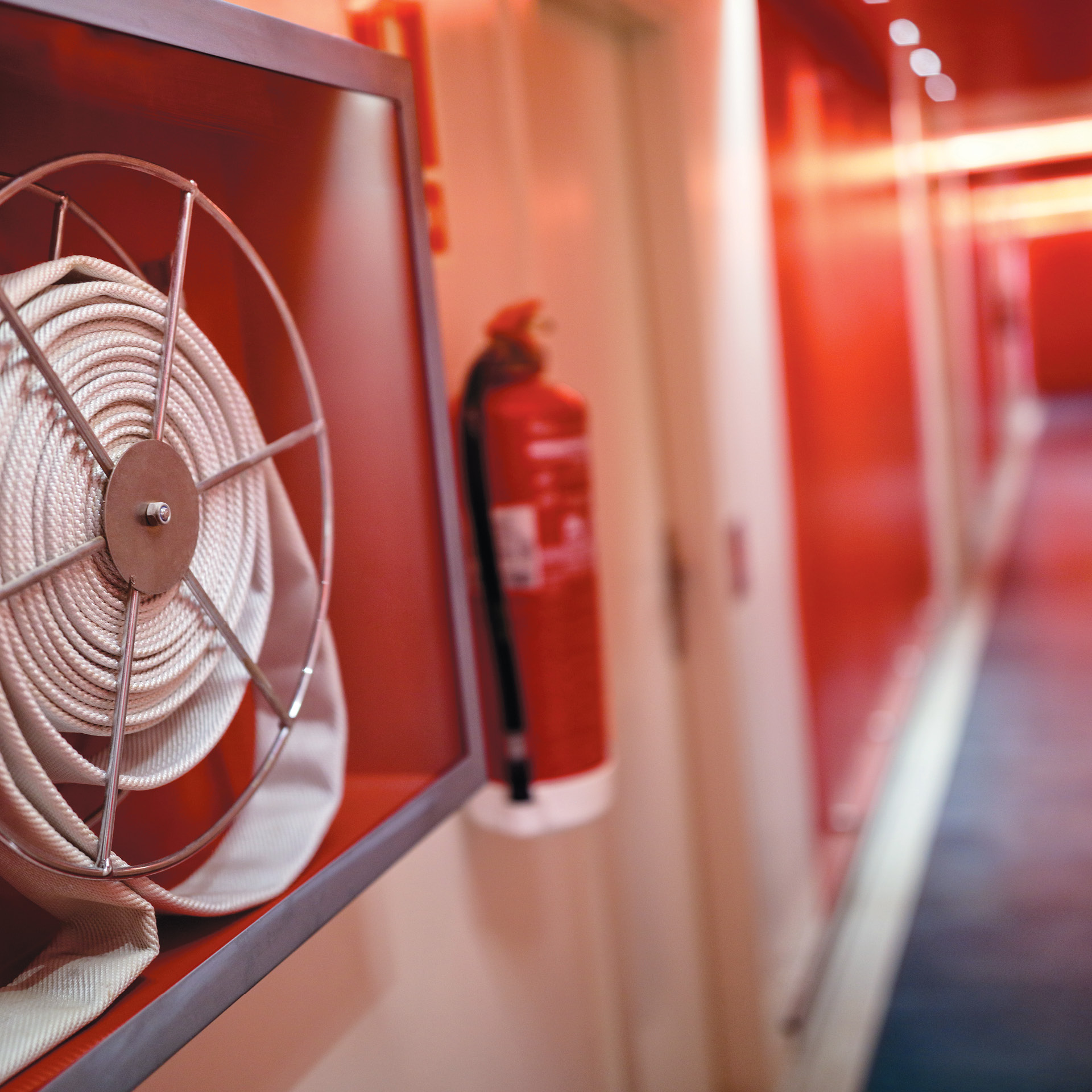 Long hallway leading to a door with fire extinguishing equipment on the wall