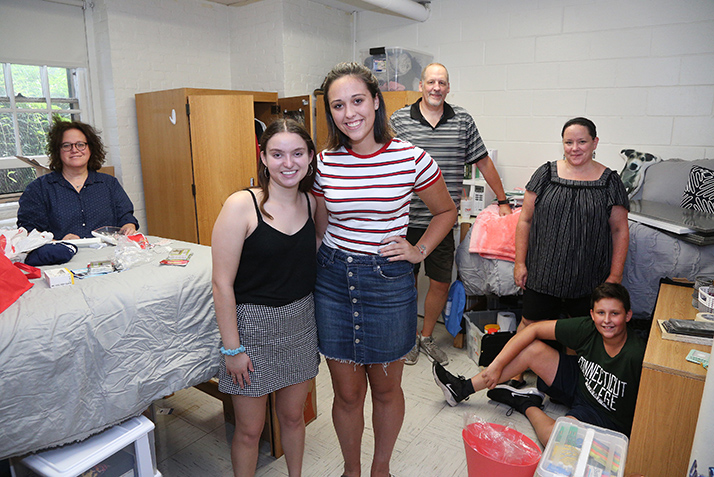 Two new roommates pose for the camera while their parents look on.