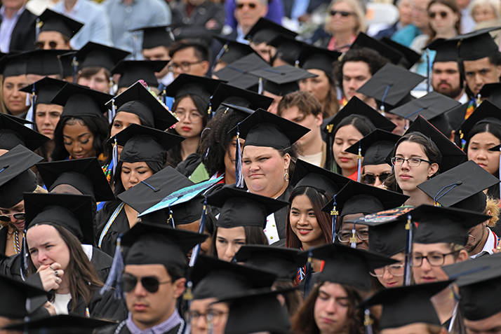 Graduates sit and listen to a speaker during commencement exercises