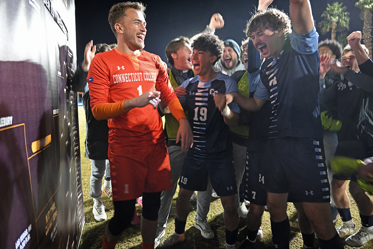 Soccer players laugh and cheer celebrating a win.