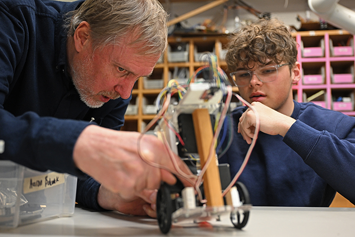 A professor examines a student's robot