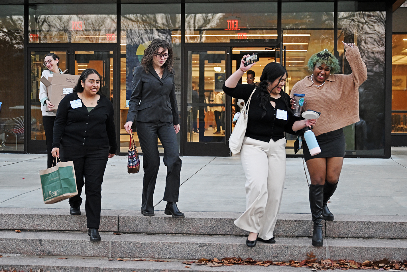 Students celebrate their success presenting at a symposium while walking down the library steps.