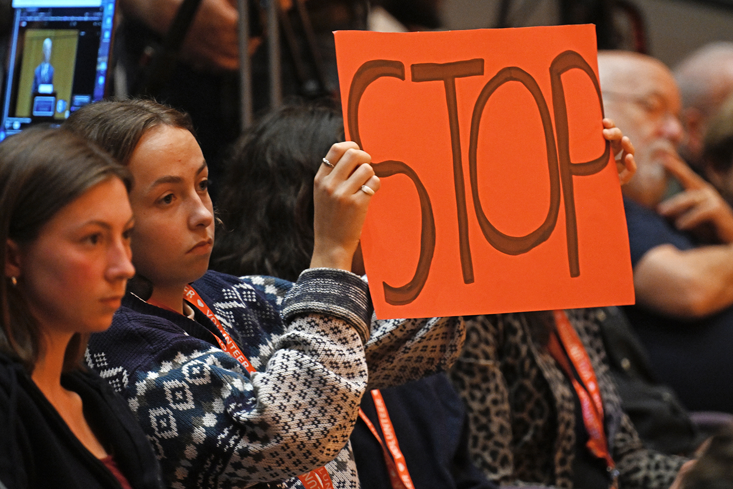 A student timekeeper holds up a sign to indicate time has expired on a debate participant's response.