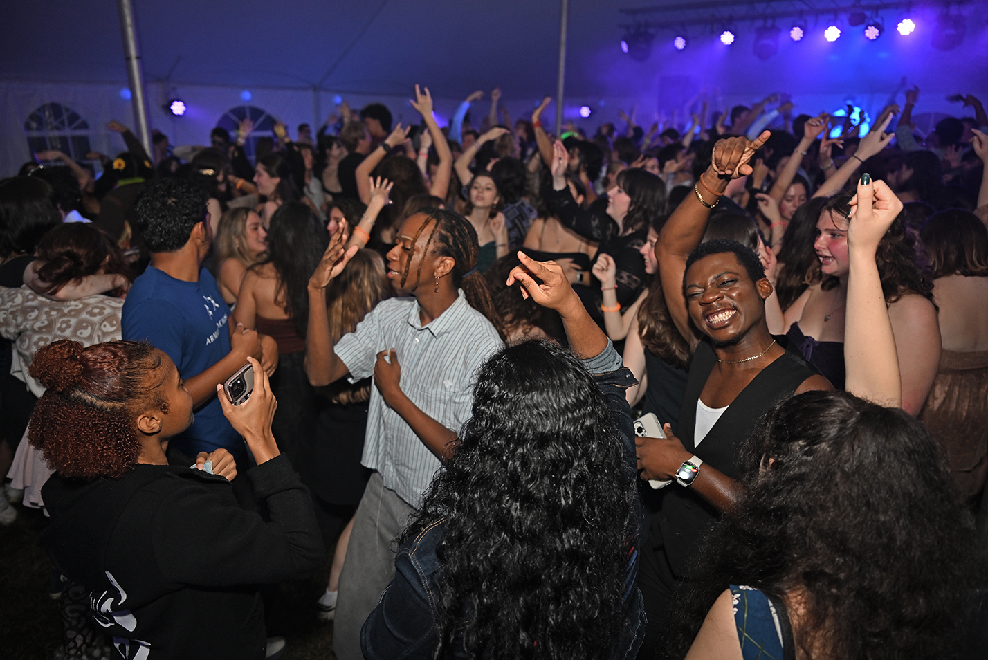 A large crowd of students dance under a tent.