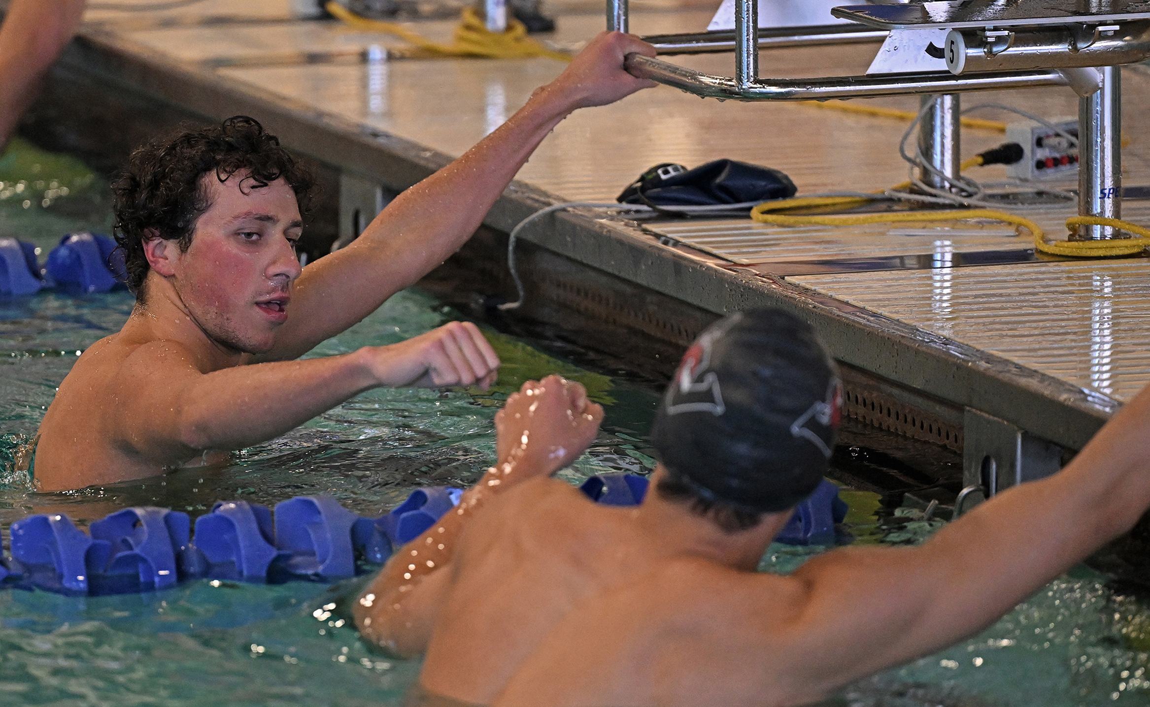 Two student swimmers fist-bump after competing in a race.