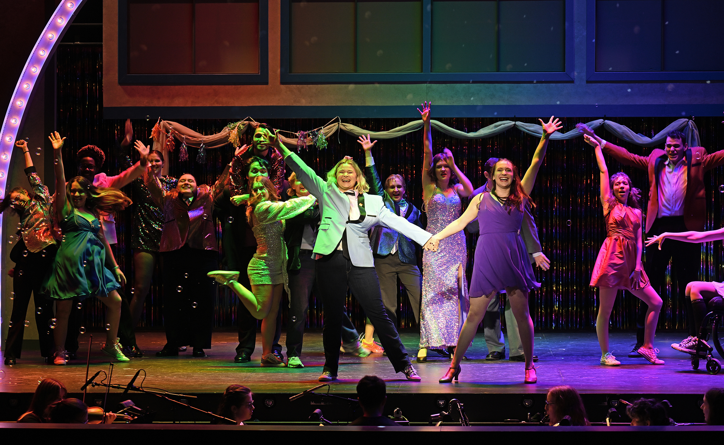 Actors dance and sing on stage in a musical theater performance