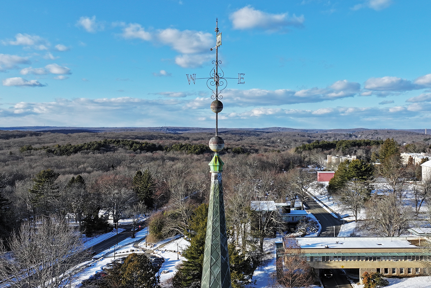 A church steeple looms high over a snow covered college campus.